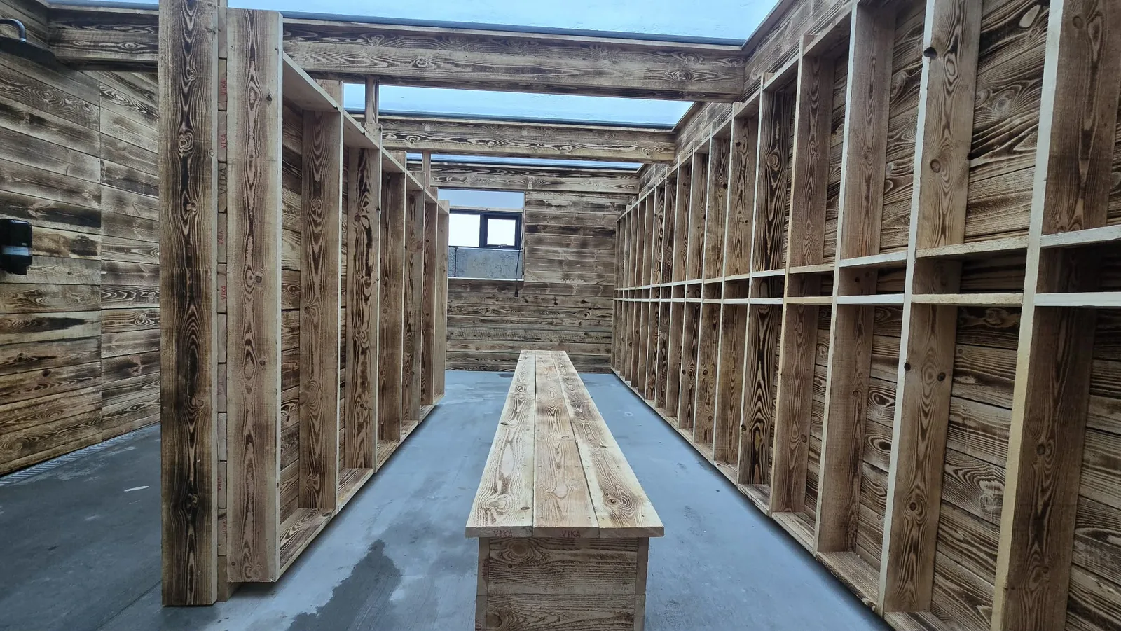 Timber changing area with a central bench and open storage at Hveradalir