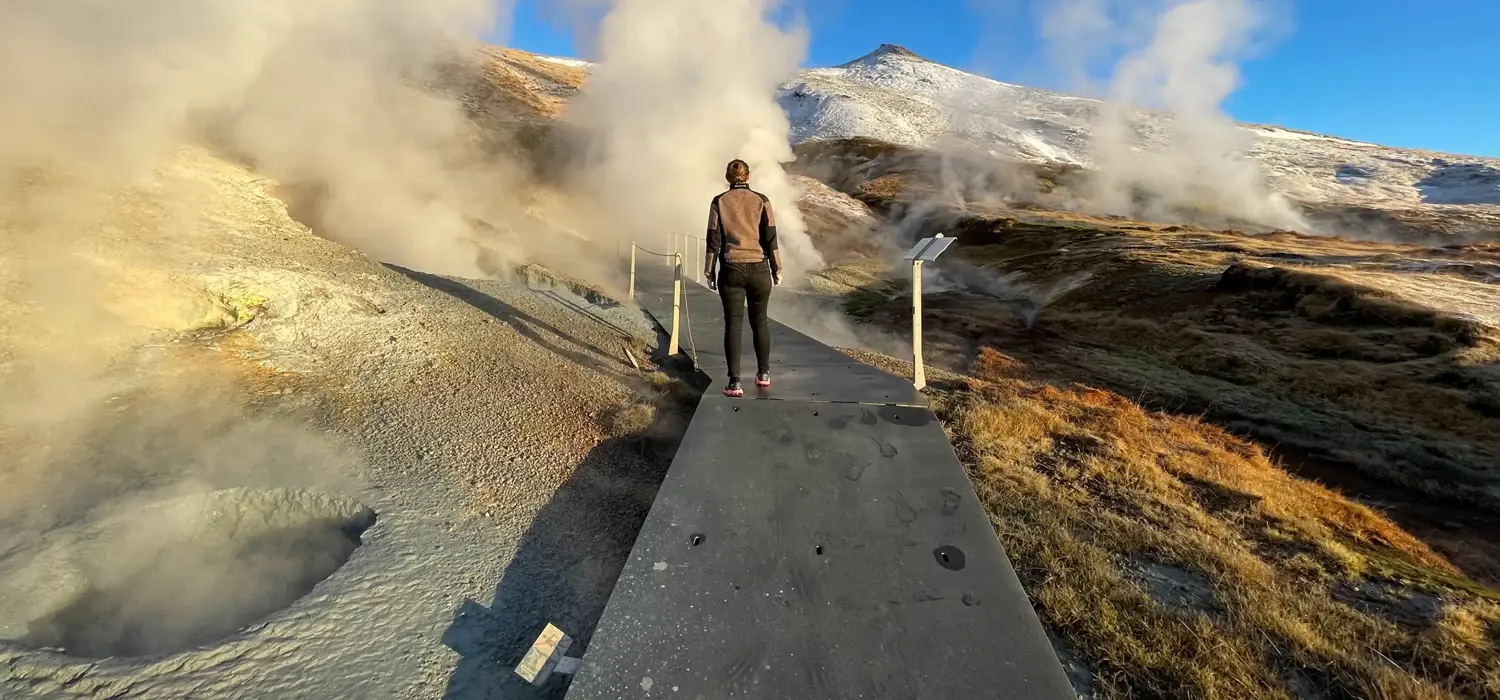 A visitor exploring the steaming geothermal valley at Hveradalir